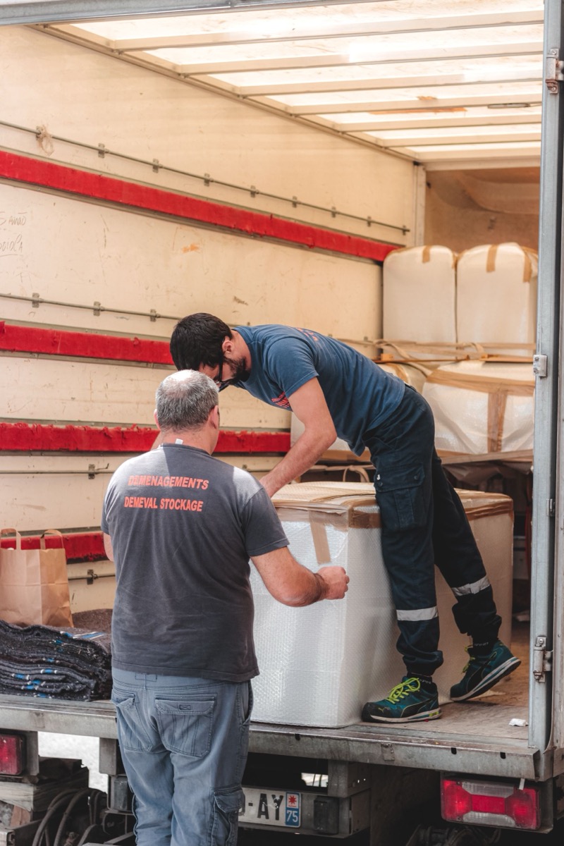 Crew loading blanket-wrapped furniture inside a moving truck