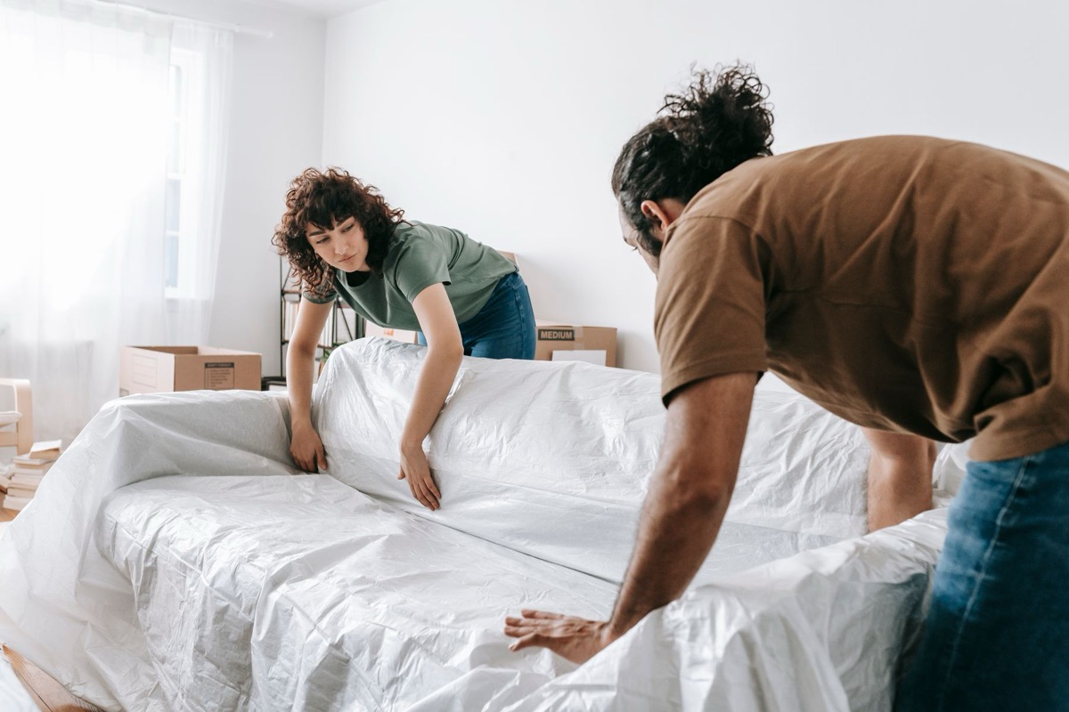 Movers covering a sofa with protective wrap before a move