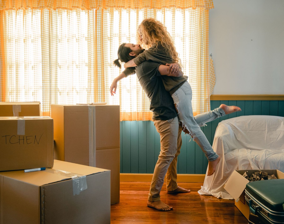 Happy couple celebrating in their new home surrounded by labeled moving boxes